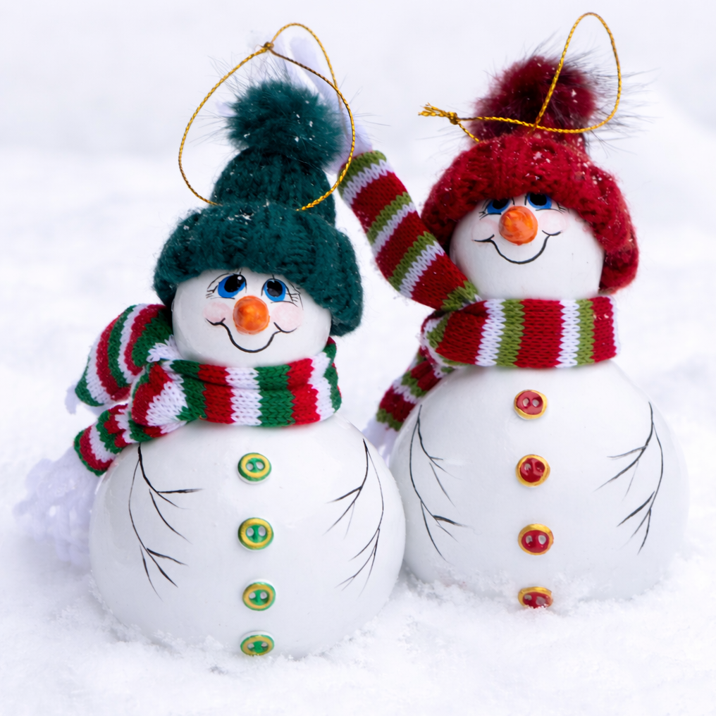 Hand painted snowman gourd ornament with red knit hat and striped scarf in snow