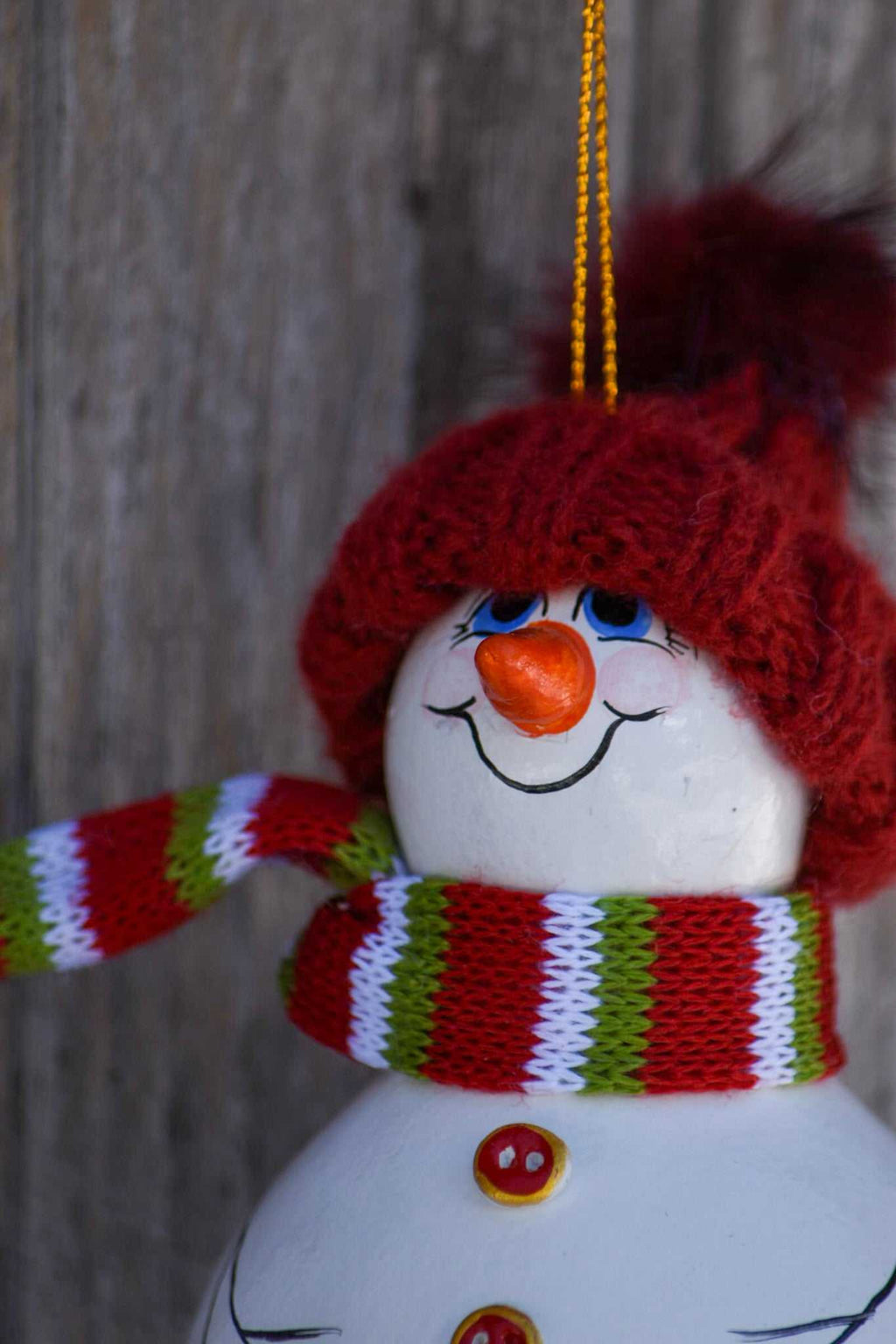 Hand painted snowman gourd ornament with red hat hanging on Christmas tree