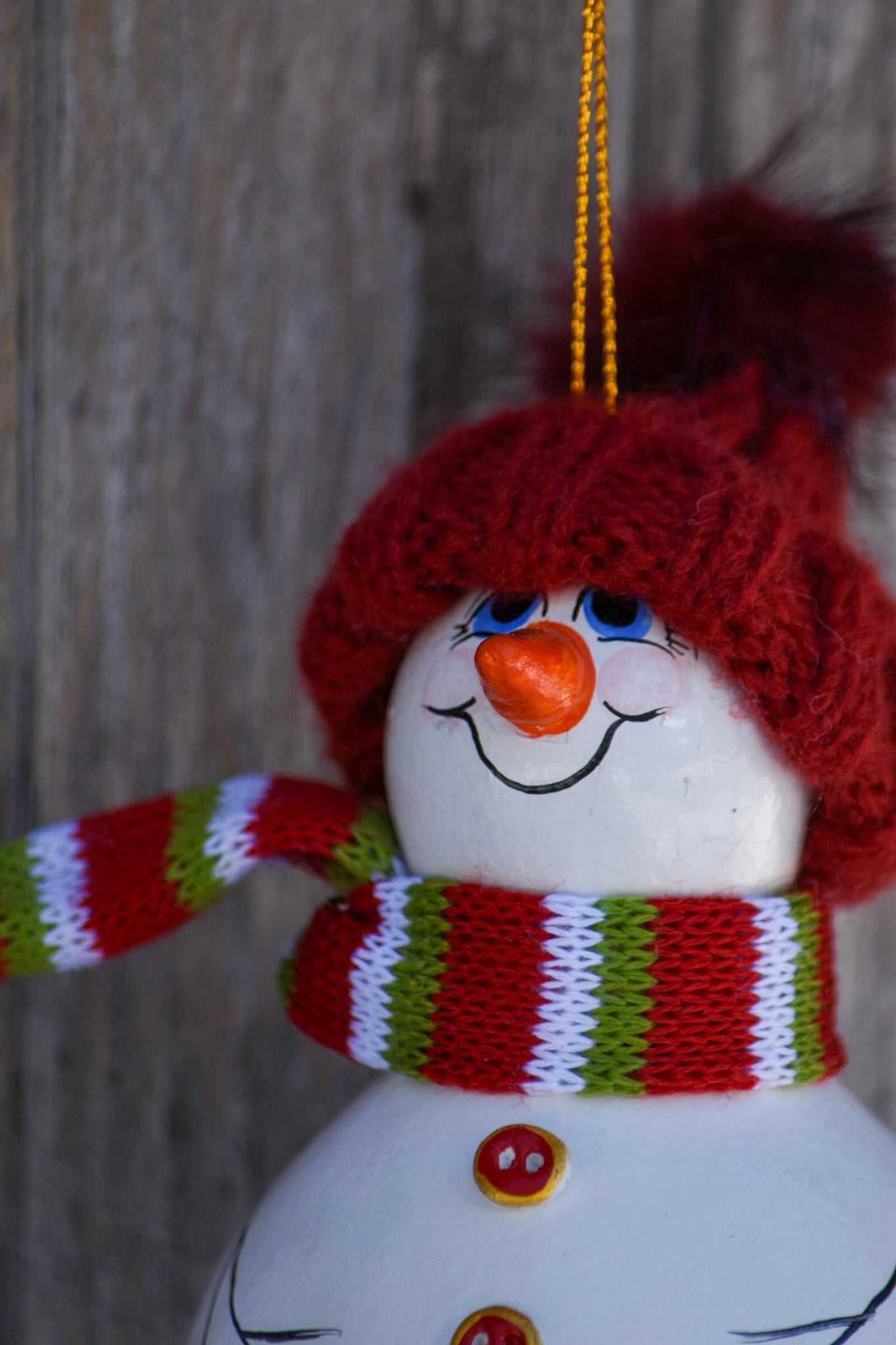 Hand painted snowman gourd ornament with red hat hanging on Christmas tree