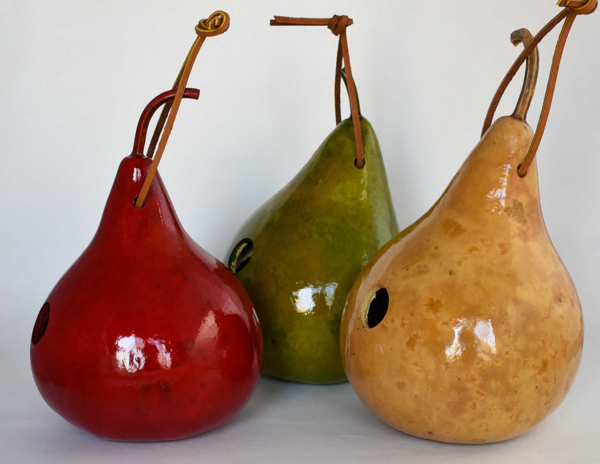 Set of three handcrafted gourd wren birdhouses in red, green, and natural colors with hanging cords and entrance holes for small birds.