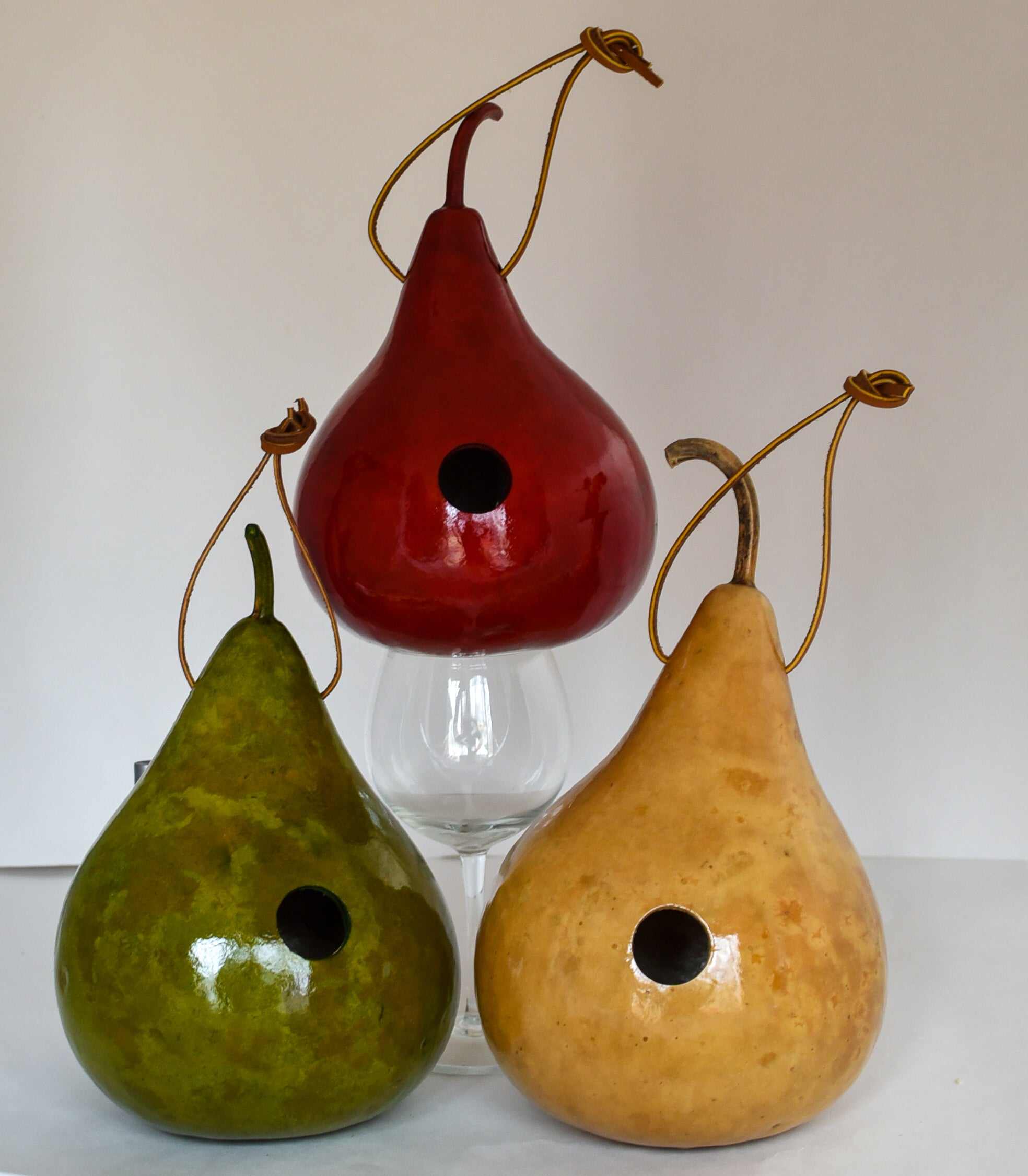 Set of three handcrafted gourd wren birdhouses in red, green, and natural colors with hanging cords and 1 1/8" entrance holes.